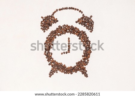 Alarm clock made of coffee beans on light background