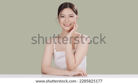 Beauty portrait of happy Asian female face with natural skin make up isolated on green background.