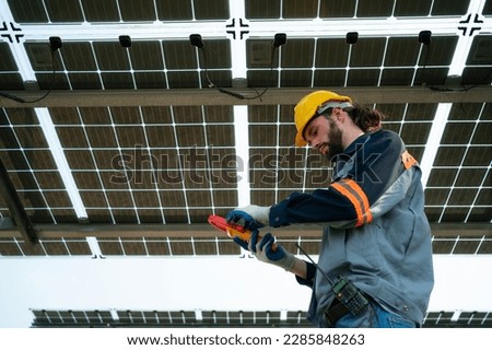 Electrical engineers are inspecting and maintaining solar cells at a solar cell panel in the middle of a hundred acres of grass.