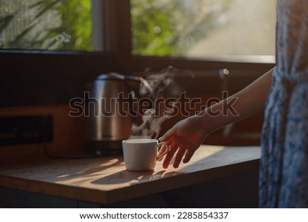 Woman is drinking coffee , morning routine. Tiny house. First property. Small apartment interior design. Minimalism. Moving in. Living alone. Charming trailer house with the morning sun Royalty-Free Stock Photo #2285854337