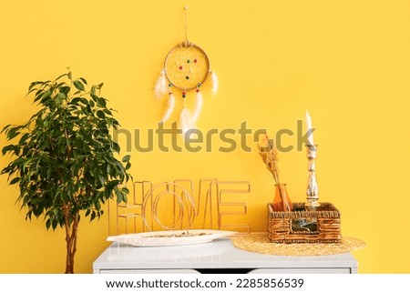 Dream catcher hanging on yellow wall in room