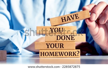 Close up on businessman holding a wooden block with "HAVE YOU DONE YOUR HOMEWORK?" message