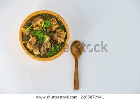 Fresh spicy lamb paya soup in a wooden bowl and ready to eat. Home made mutton soup called paya or attukaal soup in south india. Mutton soup in wooden bowl Royalty-Free Stock Photo #2285879941