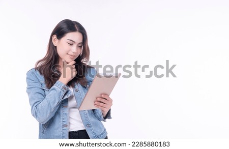 Cheerful asian woman denim jacket holding tablet thinking creative idea standing over isolated white background. Student young girl holding hand under chin education online tablet.Lifestyle technology