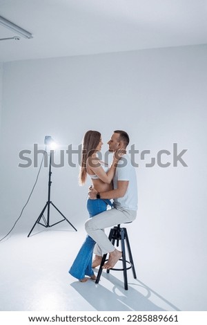 Happy young couple expecting a baby in white t-shirts and jeans on a white background. happiness of pregnancy and childbirth. A happy married couple is expecting a child