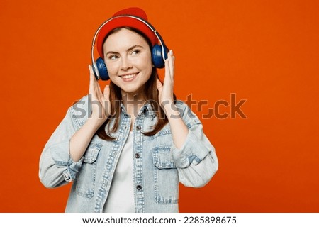 Young smiling minded calm fun pensive cheerful woman wearing denim shirt white t-shirt look aside on area raise up hands dance isolated on plain orange background studio portrait. Lifestyle concept