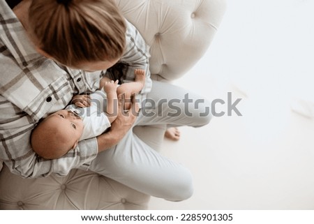 Handsome single father holding his newborn baby in white bedroom