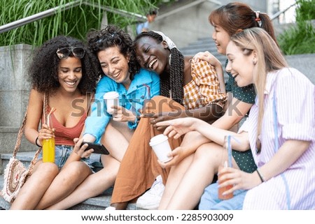Five multiethnic girls laughing and taking selfie isolated over white background