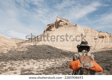 Rear View A Traveler Taking Pictures With A Backpack In The Bardenas Desert. Navarre