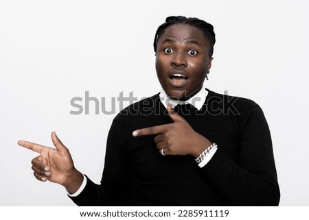 Surprised curious afro american young handsome man over white background in studio isolated pointing directing fingers side empty space banner advertisement concept.