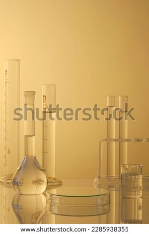 Minimal concept with laboratory glassware - test tubes and beaker filled transparent liquid, petri dishes upside down form an empty platform to display products. Front view Royalty-Free Stock Photo #2285938355