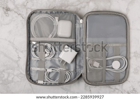 Puts wires of tablet advanced electronic equipment, phone charger in a convenient storage bag. Preparing for a business trip or vacation. Packing method for technological tools.