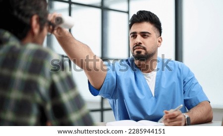 the doctor at the reception in his office measures the temperature of the patient with an electronic thermometer Royalty-Free Stock Photo #2285944151