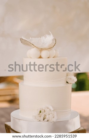 White large cake decorated with flowers and feathers for the baby