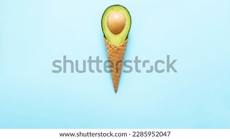 
stylish mockup with avocado in an ice cream waffle cone on a pastel blue background. creative healthy food concept. copy space
