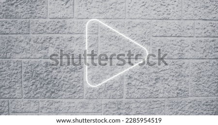 Image of white neon arrow icon on brick background. Social media and digital interface concept digitally generated image.