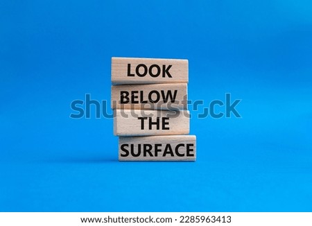 Look below the surface symbol. Concept word Look below the surface on wooden blocks. Beautiful blue background. Business and Look below the surface concept. Copy space