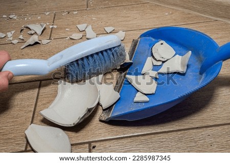 A housekeeper sweeps the broken vase with a broom