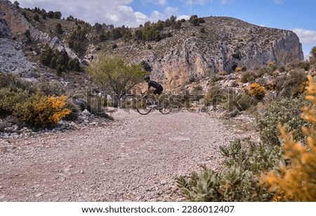 Fit male cyclist riding dirt trails on gravel bike. Man riding gravel bike on gravel road in scenic view with hills in Spain. Sport motivation.Gravel road in mountains.