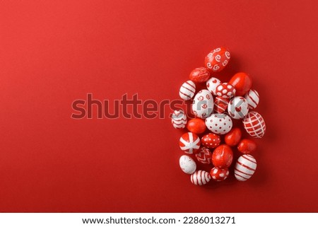 Easter backgrounds with a large egg of Easter red and white eggs on a bright red background. Copy space. Flat lay, top view.