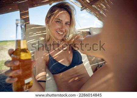 Smiling girl drink beer on the beach and take selfie