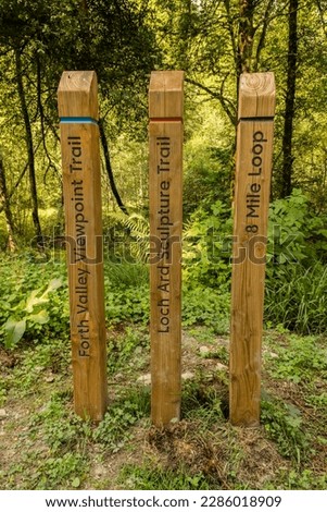 Coloured wooden trail posts highlighting different trails in a woodland in Loch Lomond and the Trossachs National Park, Scotland