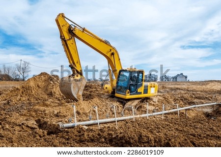 Excavator dig the trenches at a construction site. Trench for laying external sewer pipes. Sewage drainage system for a multi-story building. Digging the pit foundation.