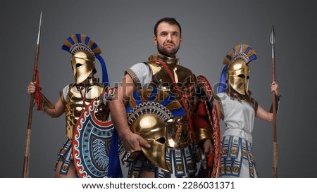 Portrait of greek troop of warlord and two warriors with bronze armors and spears.