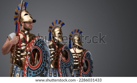 Studio shot of handsome three warriors from ancient greece dressed in bronze plate armors.