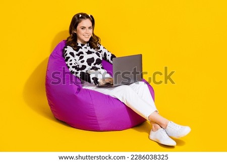 Photo of pretty sweet girl wear cow skin shirt sitting bean bag working modern device empty space isolated yellow color background