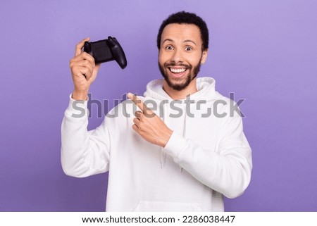 Photo of cheerful person toothy smile indicate finger hand hold controller isolated on violet color background