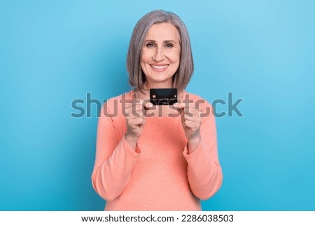 Photo of cheerful positive woman wear coral shirt showing credit card smiling isolated blue color background