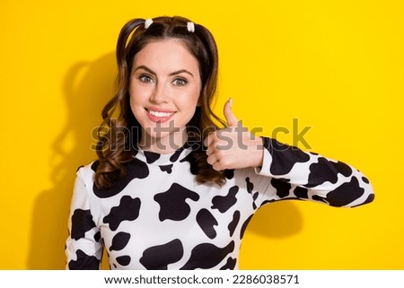 Portrait of young attractive smile lady wear cowskin shirt thumb up enjoy her hairstyle curly ponytails isolated on yellow color background