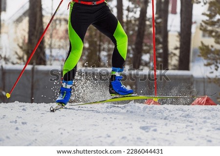 close-up legs skier athlete run on ski track, snow splashes from under skis and poles, winter sports competition