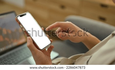 Man sitting on couch at home and using mobile phone. White empty screen for graphic display montage
