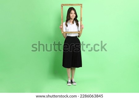 The young school girl with uniform standing on the green background.