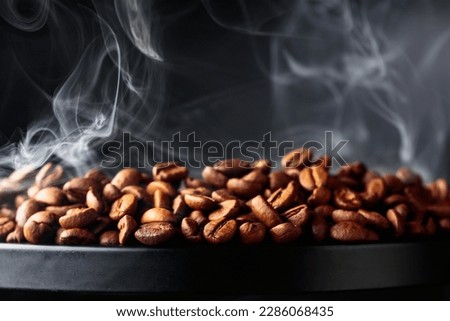 Steaming coffee beans on a black background. Selective focus. Copy space.