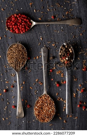 Old spoons with various seeds and spices on black background. Flat lay. Top view. Food concept. Dark mood food photography.