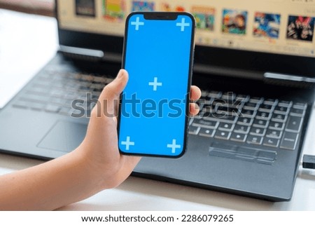 Close up teenage hands using smartphone green blue screen Chroma Key. Child scrolling over laptop app background Online entertainment education, online shopping, gaming, Mobile app, Using smartphone