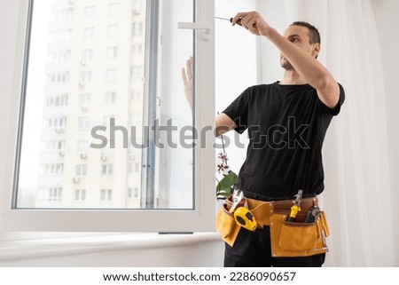 Handsome young man installing bay window in a new house construction site