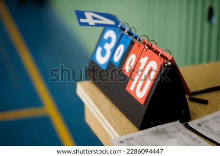 table scoreboard volleyball. Counter for volleyball, basketball and tennis counts. Plastic scoreboard for scoring in volleyball. Standing on a table in the gym. Scoreboard on a blue and red background Royalty-Free Stock Photo #2286094447