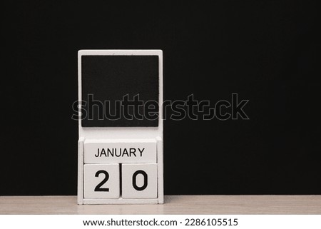 White wooden block monthly calendar with the date january 20 on the table, black blackbackground. Planning