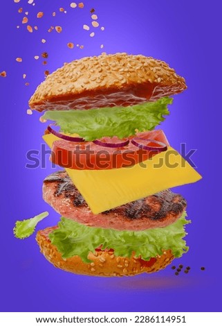 Flying hamburger. Consists of a bun with sesame seeds, grilled cutlets, green salad, cheese, tomatoes, onions and tomato sauce on a dark background. vertical frame.
