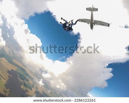 Photo of two skydivers jumping in tandem from a plane in the air.