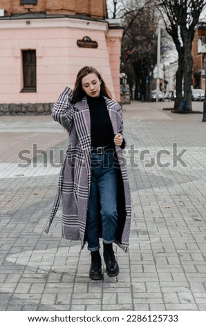 a girl in a coat walks around the city