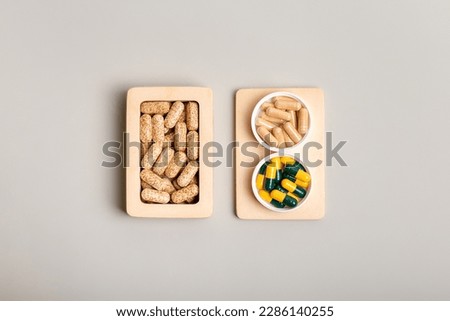 Vitamins and nutrients supplements in small wooden box and minerals capsules on wooden desk from above on light background. Minimalistic picture with vitamins to protect health from illnesses.