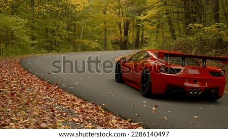 Red supercar hurtles on the roads of an autumn forest Royalty-Free Stock Photo #2286140497