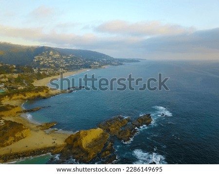 aerial shot of a gorgeous summer landscape at the beach with vast blue ocean water and homes on the mountains along the coast at sunset at Treasure Island Beach in Laguna Beach California USA