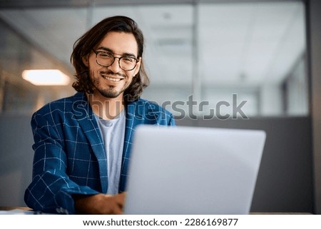 Happy businessman using computer while working in the office and looking at camera. Copy space. Royalty-Free Stock Photo #2286169877