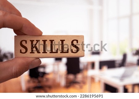 Businessman shows a wooden block with the word skills. Business or job qualification, competence or leadership skills concept. Royalty-Free Stock Photo #2286195691
